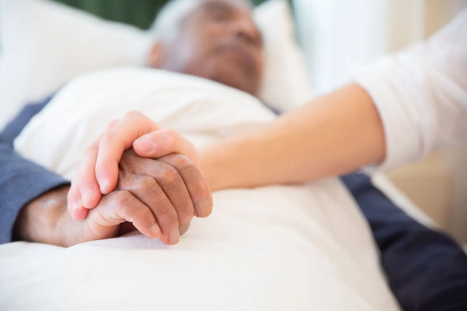 Une main jeune tenant avec douceur la main d'une personne âgée